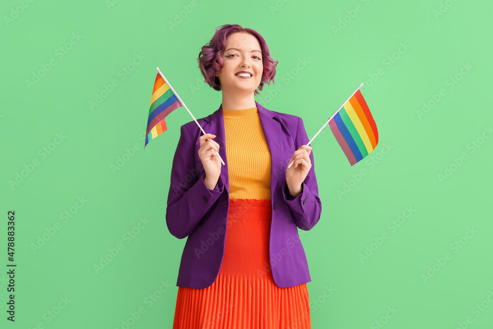 Young woman with LGBT flags on green background Young woman with LGBT flags on green background