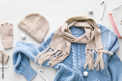 Stylish winter clothes and Christmas decor on light background