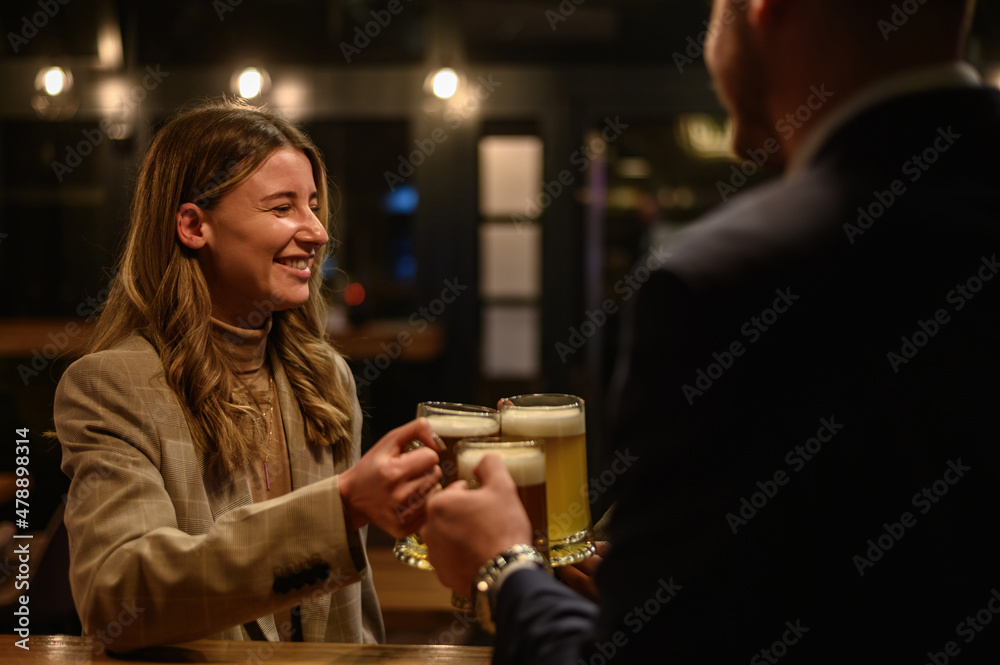 Cheerful colleagues drinking beer in the bar together after work and using a tablet Cheerful colleagues drinking beer in the bar together after work and using a tablet