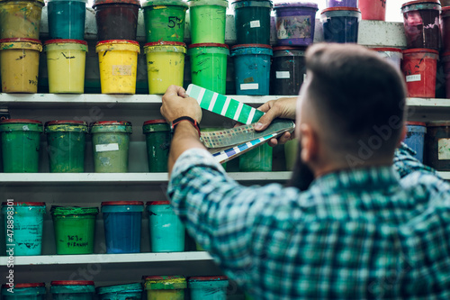 Canvas Print Male worker mixing colors for screen printing in a workshop