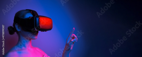 woman in vr glasses stretching her finger to touch something in virtual world photo