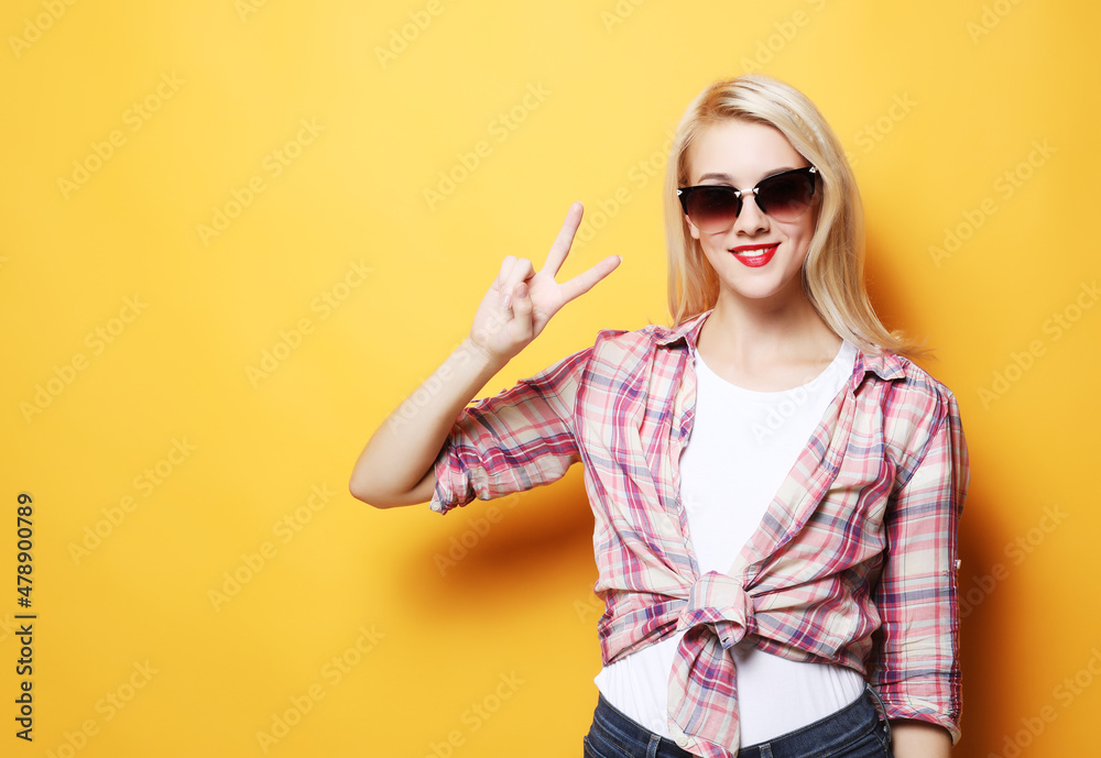 Portrait of gorgeous woman looking at camera with smile and showing peace sign with fingers Portrait of gorgeous woman looking at camera with smile and showing peace sign with fingers