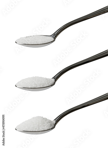 Set of three teaspoons of refined white sugar showing an angled view of level, rounded and heaped measurements isolated on a white background