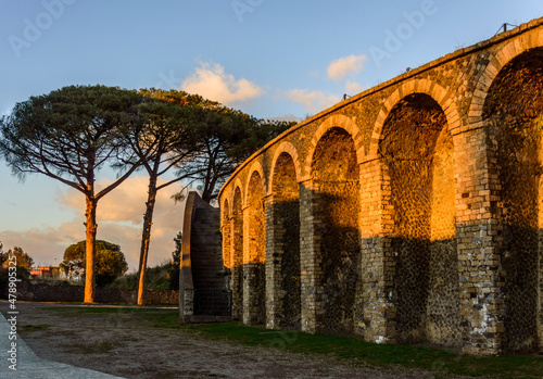 Sunset sky above the ancient roman amphitheater of Pompei in Italy  and evening dawn shadows on it  pine trees in front of it