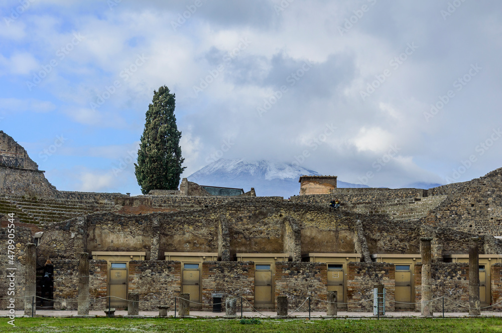 Blue sky with clouds over the ruined wall of the theatre in the ancient Roman city of Pompeii and mount Vesuvius, Italy