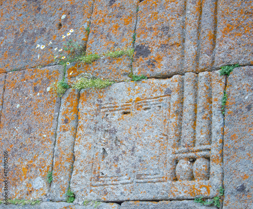 Carved stone wall with moss andblooming flowers of Gergeti Trinity Church closeup © Dmitry