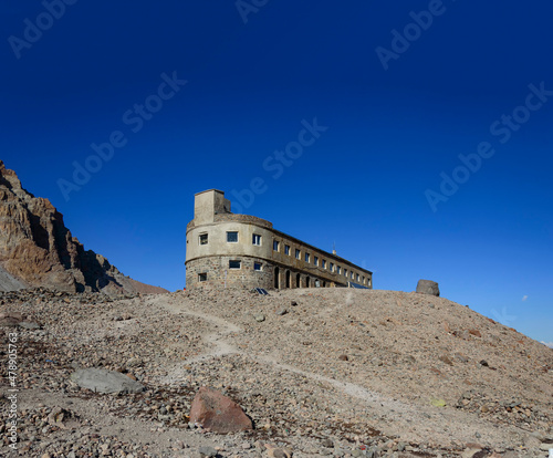 Blue sky, grey and brown rocks and stones and a trail to Betlemi Hut (Meteo station) shelter near Mount Kazbek in Georgia photo