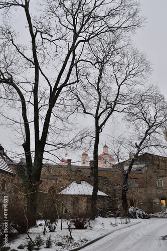 Vilnius old town yard and house road in a cloudy winter evening. brick fence, naked trees, old churches and bell towers on the horizon