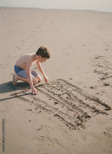 young boy draws an american flag in the sand 2 photo