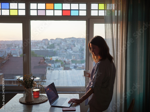 Woman looking to the window with laptop on the table photo