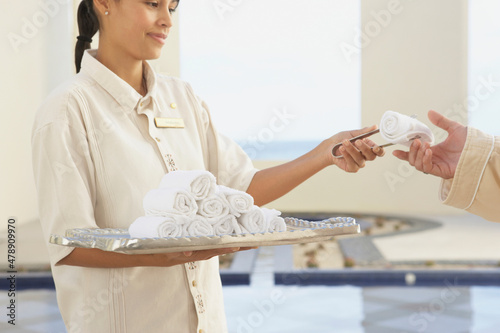 Hotel service employee offering towel to guest at spa photo