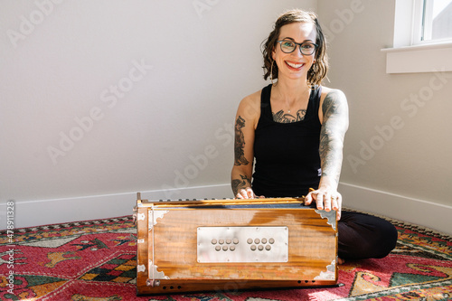 Smiling woman sitting on floor playing harmonium photo