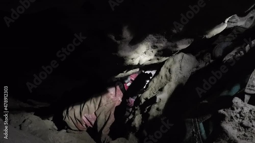 Female expedition caver passes gear bags down steep tight passage photo