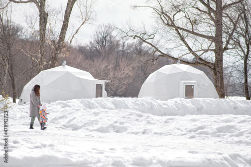 Mom and little daughter are walking through winter glamping.