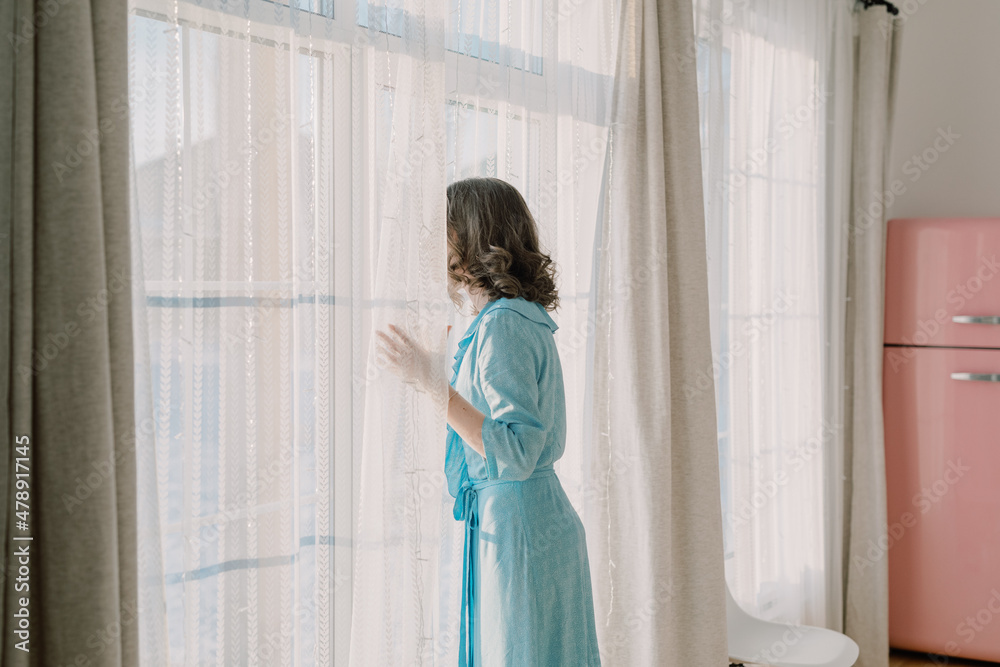 Woman in a pretty kitchen looking out the window Woman in a pretty kitchen looking out the window