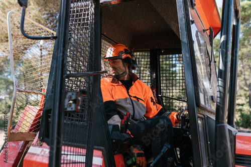Male worker driving tractor in forest