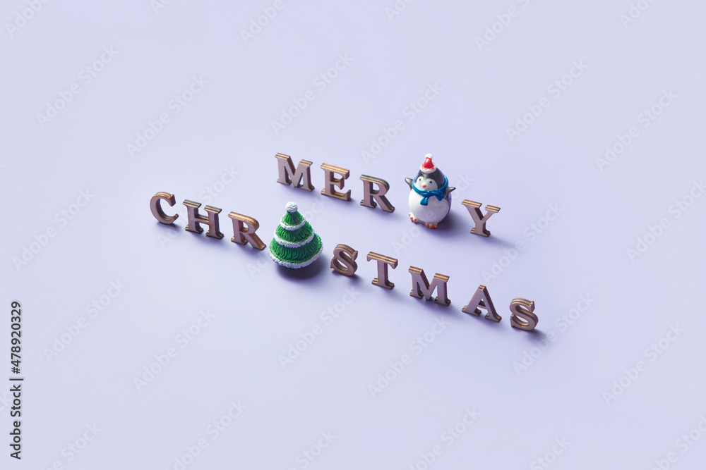 Merry christmas phrase with ceramic tree and penguin