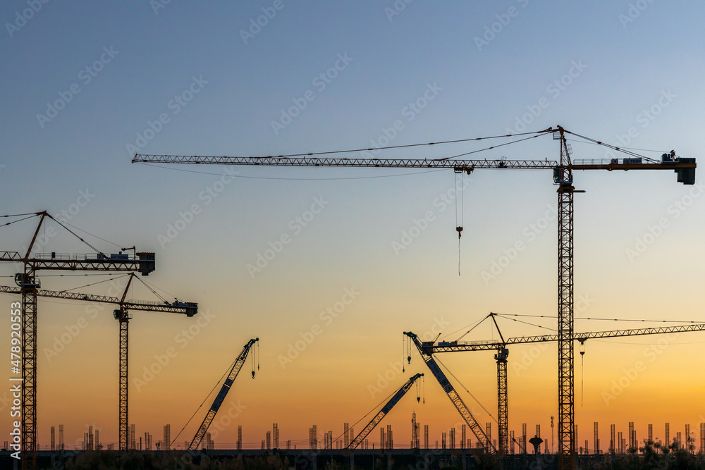 Construction site with tower crane and building construction site silhouette at sunrise, construction sites and many cranes are working in the industry new building business. Construction site with tower crane and building construction site silhouette at sunrise, construction sites and many cranes are working in the industry new building business.