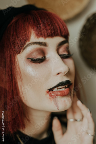A woman getting ready for halloween and wearing vampire makeup