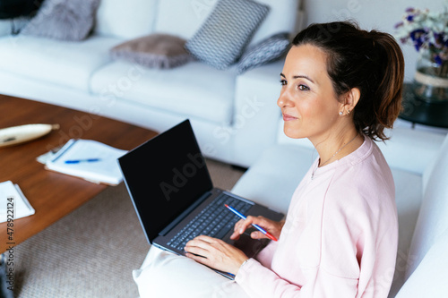 Pensive Hispanic woman working on laptop photo