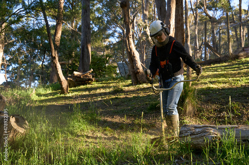 Woman using brush cutter with handle bar grip photo