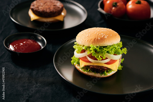 Hamburger with beef meat burger and fresh vegetables on dark background. Tasty fast food