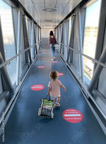 A little girl follows her mum through an airbridge.  photo