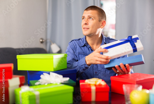 Cheerful adult man opening box with gift, celebrating his birthday