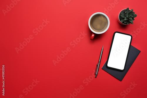 Mock up smart phone, coffee cup and notebook on red background with copy space for text.