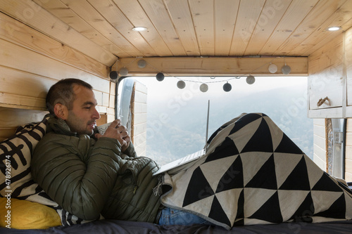 Man Drinking Tea in Bed of a Camper Van photo