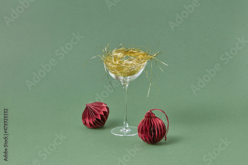 Glass with gold tinsel and red baubles on background photo