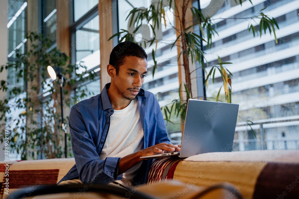 Young man working from cafeteria with laptop

