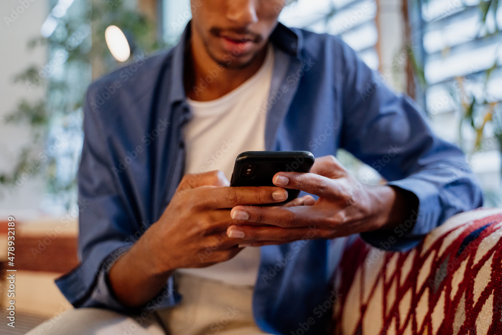 Crop image of Young man texting on phone in cafeteria Crop image of Young man texting on phone in cafeteria