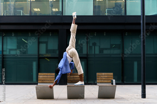 Stylish man doing yoga pose on bench photo