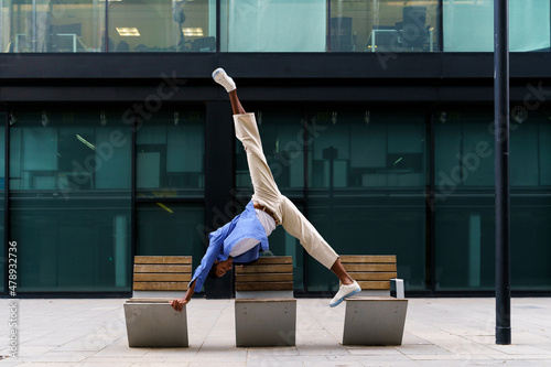 Stylish man doing yoga pose on bench photo