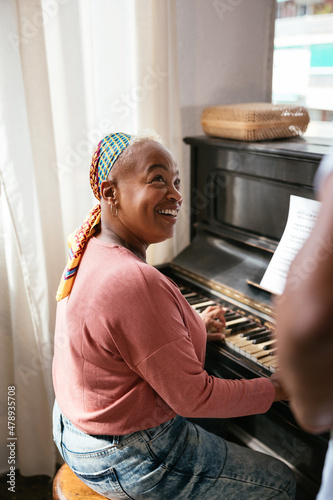 Mature woman playing piano near teacher