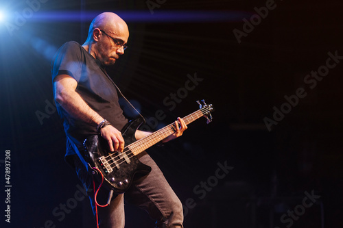 Serious bass player in stage with colorful lights photo