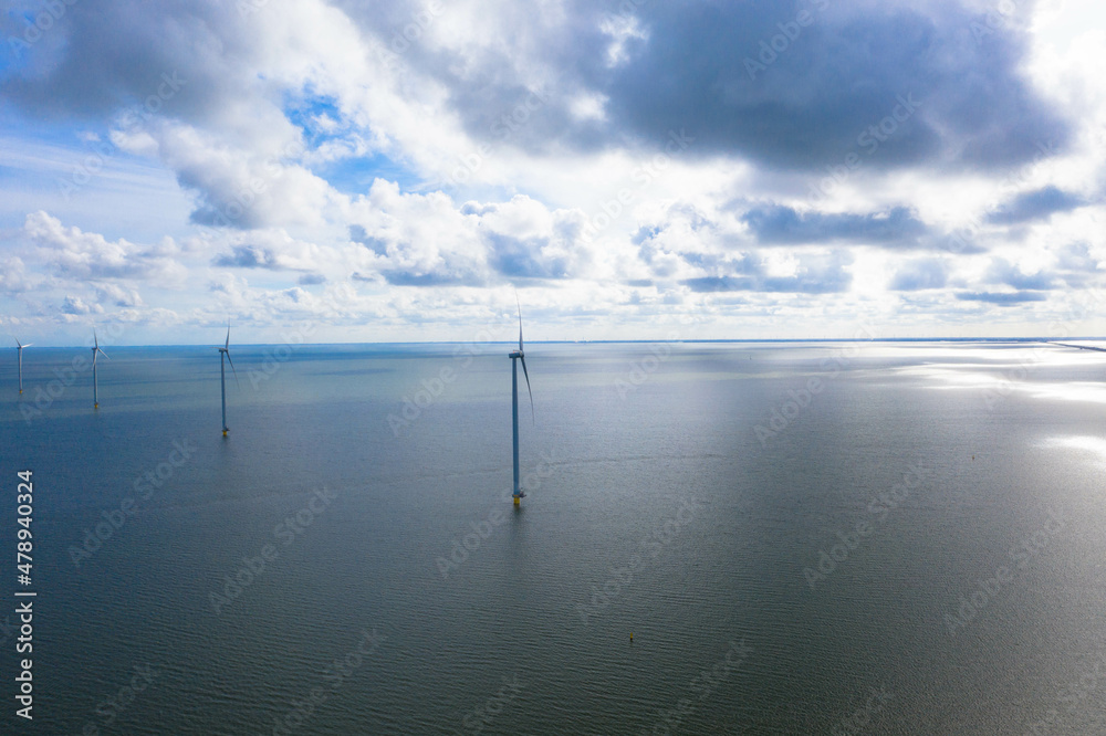 A birds eye view of the wind turbine. Drone view in the Fryslan wind farm, a windmill farm in the IJsselmeer in the Netherlands agianst dark rainy clouds. Sustainable development, renewable energy.