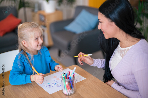 Woman helping girl to draw picture