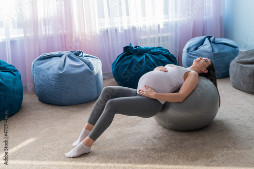 Beautiful european woman doing pregnant exercises. Expectant mother is doing exercises with a fitness sword. Yoga for expectant mothers.