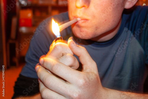 Young man lighting a marijuana cigarette photo
