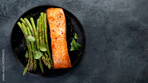Baked salmon with asparagus on gray background.