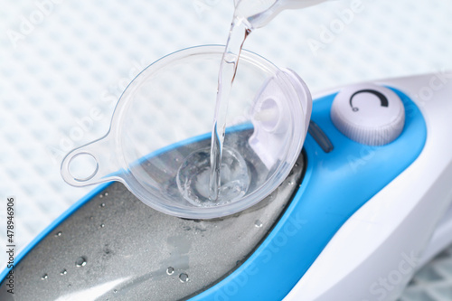 A man pours distilled water into a container of a steam cleaner, steam mop.
