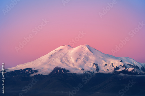 The top of Mount Elbrus. The Caucasus Mountains. View of Elbrus from the Bermamyt plateau. A rock and a snow-covered sleeping volcano.Elbrus in the rays of a pink dawn.