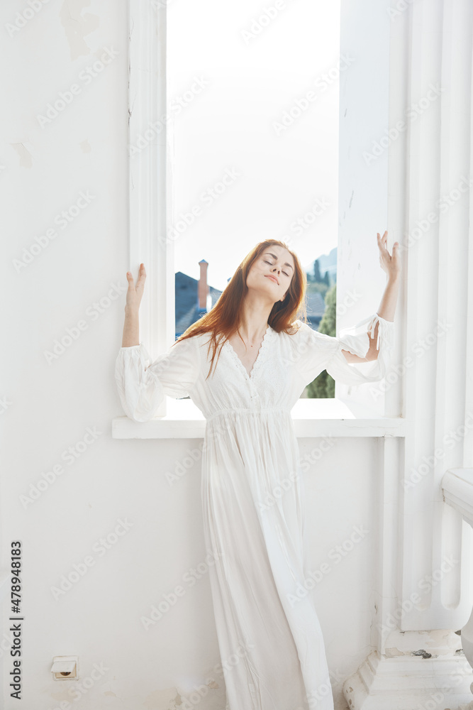 Woman in white dress near window posing romance of the sun