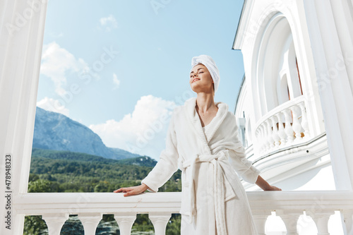 Portrait of gorgeous woman in a white robe on the balcony bit on green nature Lifestyle