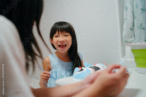 Mother painting mask with little girl photo