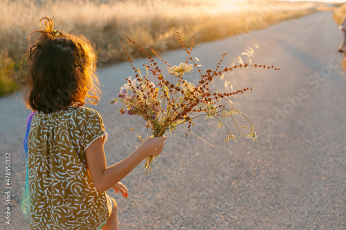 little girl with wild flowers in hand iat sunset photo