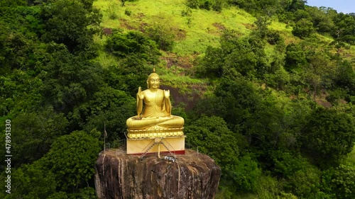 A statue of a seated golden Buddha on a rock in a mountain temple. Aluvihara, Matale, Central Province, Sri Lanka. photo