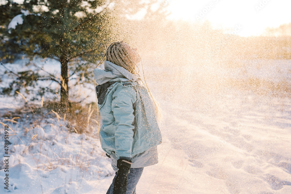 Woman with blond braids and blue jacket embracing snow Woman with blond braids and blue jacket embracing snow